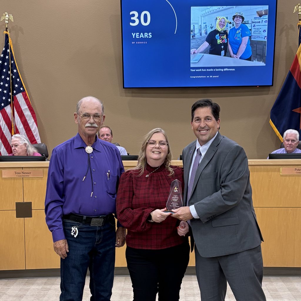 Three people pose with an award, celebrating 30 years of service